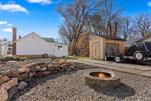 View of property exterior featuring a shed and a fire pit