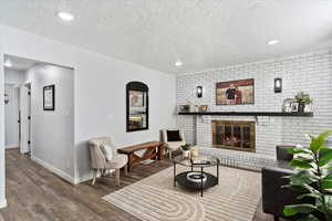 Living room with a fireplace, wood-type flooring, and a textured ceiling