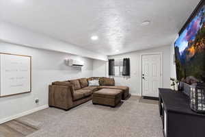 Carpeted living room with lofted ceiling, a textured ceiling, and a wall unit AC