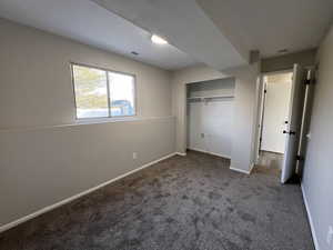 Unfurnished bedroom with dark colored carpet and a closet