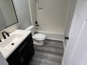 Full bathroom featuring hardwood / wood-style flooring, vanity, toilet, and shower / bath combination