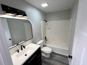 Full bathroom featuring hardwood / wood-style floors, vanity, toilet, and tub / shower combination