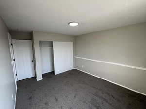 Unfurnished bedroom with a closet and dark carpet