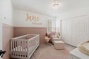 Bedroom featuring a notable chandelier, light hardwood / wood-style floors, a crib, and a closet