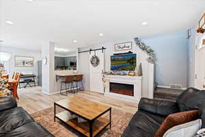 Living room with a barn door and light hardwood / wood-style floors