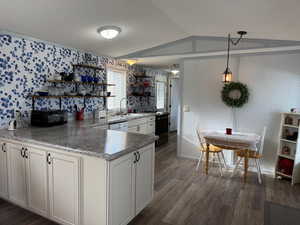 Kitchen with dark hardwood / wood-style flooring, white cabinetry, hanging light fixtures, and lofted ceiling