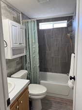 Full bathroom featuring vanity, wood-type flooring, a textured ceiling, and shower / bath combo