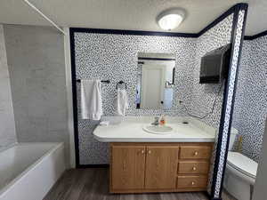 Bathroom featuring hardwood / wood-style floors, vanity, a textured ceiling, and toilet