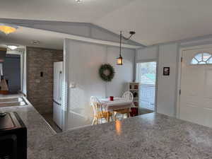 Kitchen featuring pendant lighting, lofted ceiling, dark wood-type flooring, white refrigerator, and a textured ceiling