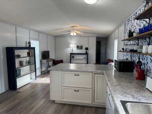 Kitchen featuring white cabinetry, ceiling fan, dark hardwood / wood-style floors, a textured ceiling, and vaulted ceiling