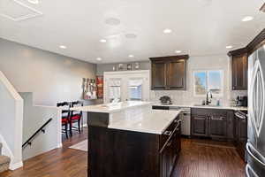 Kitchen with sink, dark hardwood / wood-style floors, decorative backsplash, a kitchen island, and stainless steel appliances