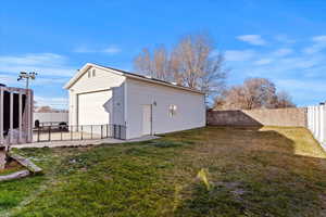 Rear view of property with a garage, a yard, and an outbuilding