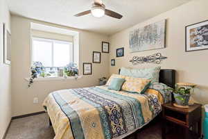 Carpeted bedroom featuring ceiling fan and a textured ceiling