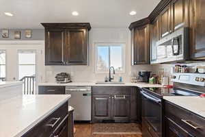 Kitchen featuring dark hardwood / wood-style flooring, decorative backsplash, sink, and appliances with stainless steel finishes