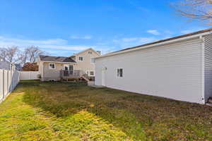 Rear view of property featuring a lawn and a deck