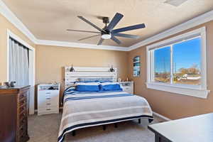 Carpeted bedroom featuring ceiling fan, a textured ceiling, and ornamental molding