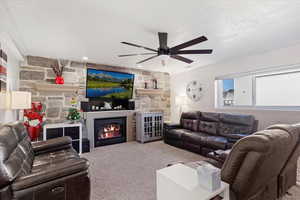 Living room with a stone fireplace, carpet floors, and ornamental molding