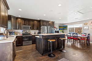 Kitchen with dark hardwood / wood-style flooring, a center island, stainless steel appliances, and a breakfast bar area