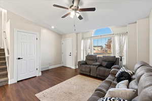 Living room featuring dark hardwood / wood-style flooring, vaulted ceiling, and ceiling fan