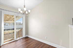 Unfurnished dining area with a notable chandelier and dark wood-type flooring