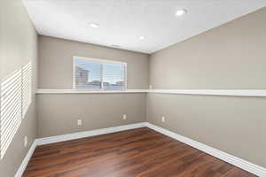 Unfurnished room with a textured ceiling and dark hardwood / wood-style floors