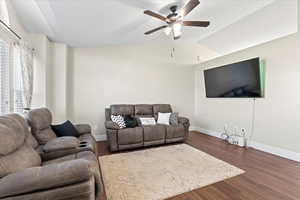 Living room featuring ceiling fan, dark hardwood / wood-style flooring, and lofted ceiling