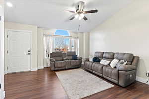 Living room featuring ceiling fan, dark hardwood / wood-style flooring, and lofted ceiling