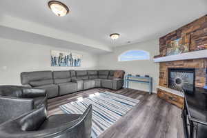 Living room with a stone fireplace and dark hardwood / wood-style floors