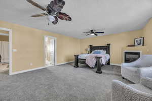 Bedroom featuring carpet flooring, ceiling fan, a textured ceiling, and ensuite bath