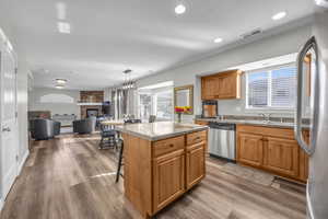 Kitchen with pendant lighting, a center island, a fireplace, light hardwood / wood-style floors, and stainless steel appliances