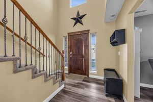 Foyer featuring a towering ceiling and dark wood-type flooring