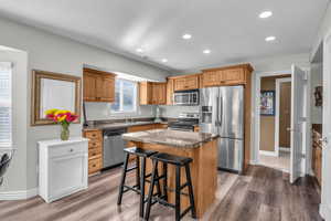 Kitchen featuring a center island, sink, a breakfast bar area, appliances with stainless steel finishes, and hardwood / wood-style flooring