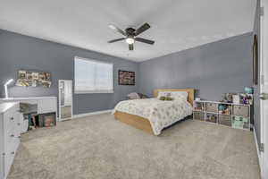 Carpeted bedroom featuring ceiling fan