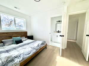 Bedroom with light hardwood / wood-style floors and connected bathroom