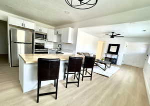 Kitchen with a breakfast bar, wooden counters, kitchen peninsula, white cabinetry, and stainless steel appliances