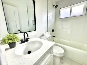 Full bathroom with vanity, toilet, and tiled shower / bath combo