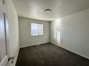 Carpeted spare room featuring a textured ceiling