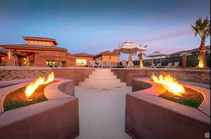 Patio terrace at dusk featuring a fireplace and a fire pit