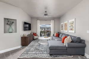 Carpeted living room featuring a textured ceiling and ceiling fan