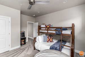 Bedroom featuring a textured ceiling, light colored carpet, and ceiling fan