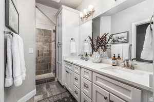 Bathroom featuring tile patterned flooring, a tile shower, and vanity