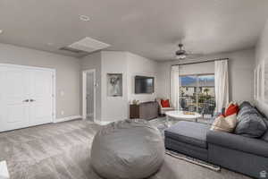 Living room featuring light carpet, ceiling fan, and a textured ceiling