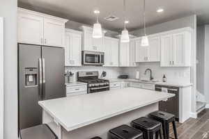 Kitchen featuring a breakfast bar area, white cabinetry, sink, and stainless steel appliances