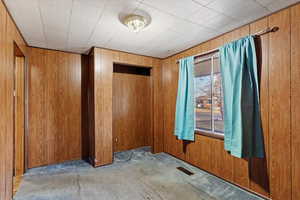 Carpeted empty room featuring wood walls