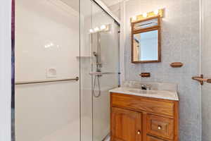 Bathroom featuring tile walls, vanity, and an enclosed shower