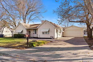 View of front of house with a garage, an outbuilding, and a front lawn