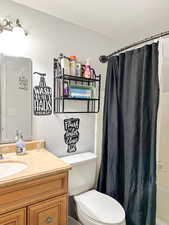 Full bathroom featuring shower / bath combination with curtain, vanity, and toilet