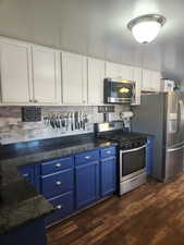 Kitchen featuring white cabinetry, blue cabinets, and appliances with stainless steel finishes