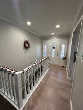 Foyer featuring light wood-type flooring, plenty of natural light, and crown molding