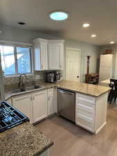 Kitchen with white cabinets, dishwasher, sink, and light hardwood / wood-style flooring